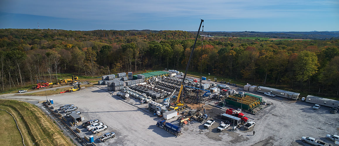 Aerial photograph of a yard with a crane and dump trucks.