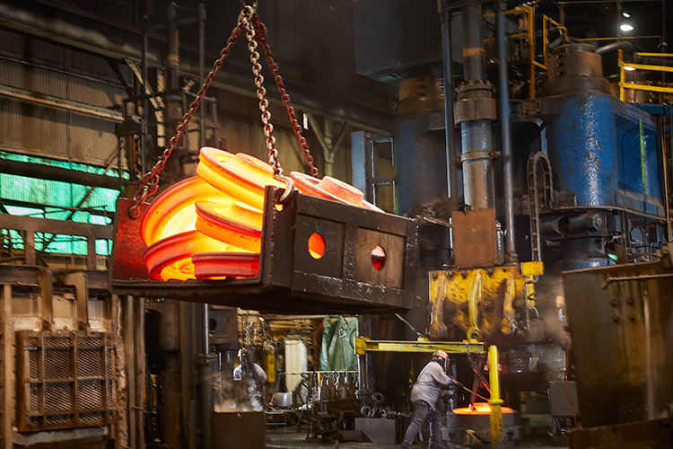 Molten train wheels being lifted by a crane.