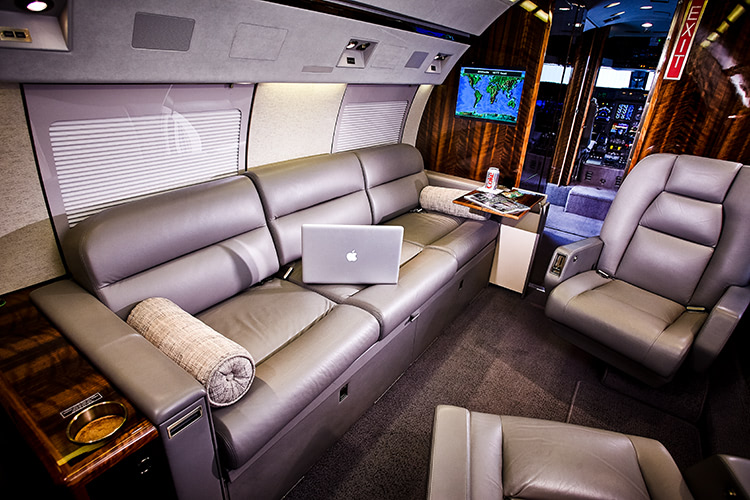 Interior shot of a private jet with a Macbook Pro open on a couch.
