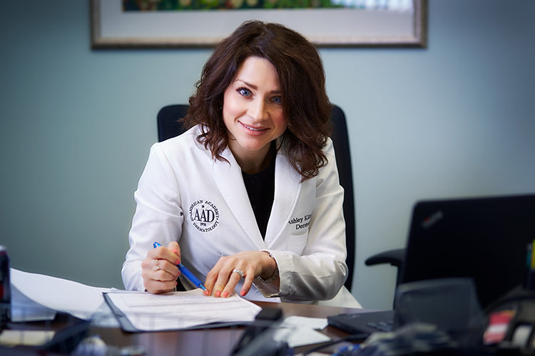 Dermatologist at her desk writing.