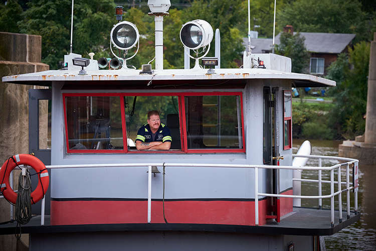 A barge pilot resting on an open window on his barge.